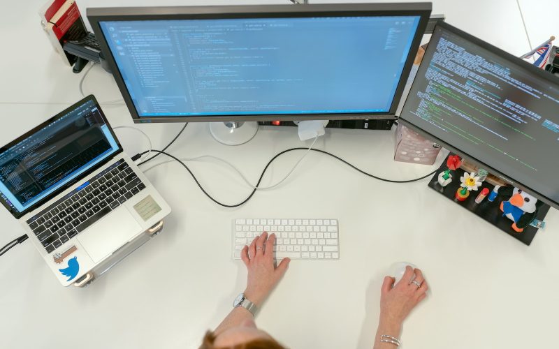 person using macbook pro on white table