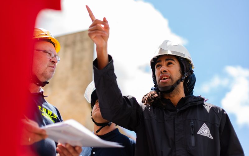 man in black jacket wearing yellow hard hat